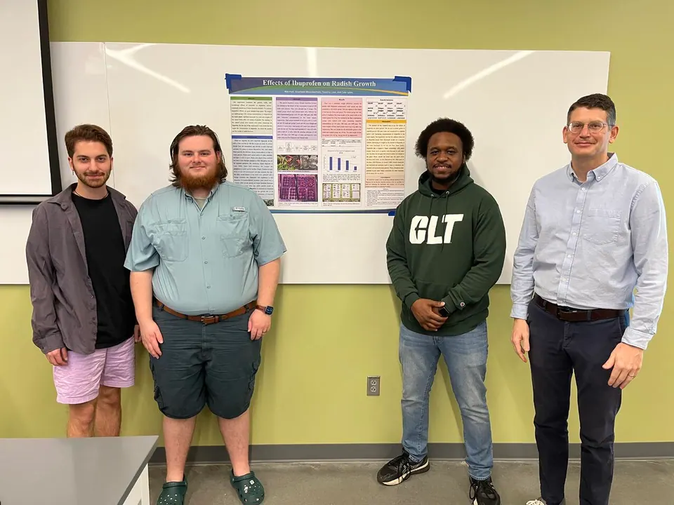 Cole Lyons, Timothy Love, Ren Hart, and Shaaheen Khosrowshahi standing together after presenting their collaborative radish-growth study at UNC Charlotte.